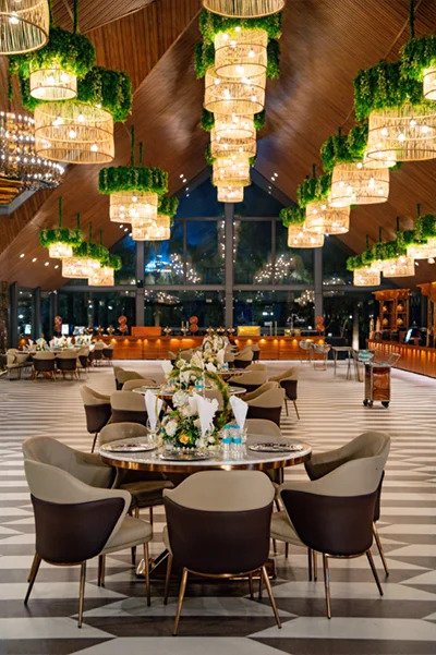 Home 6 Hawaii Glass House indoor banquet hall with rattan pendant chandeliers and round dining setup, Mallu Farms Chattarpur